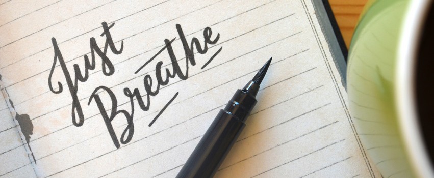 JUST BREATHE brush calligraphy in notebook with cup of coffee on desk