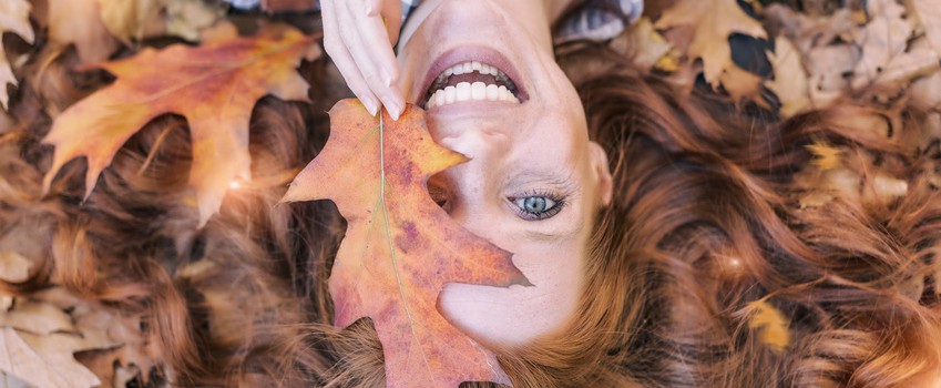 young red hair beauty lying in orange autumn leafes